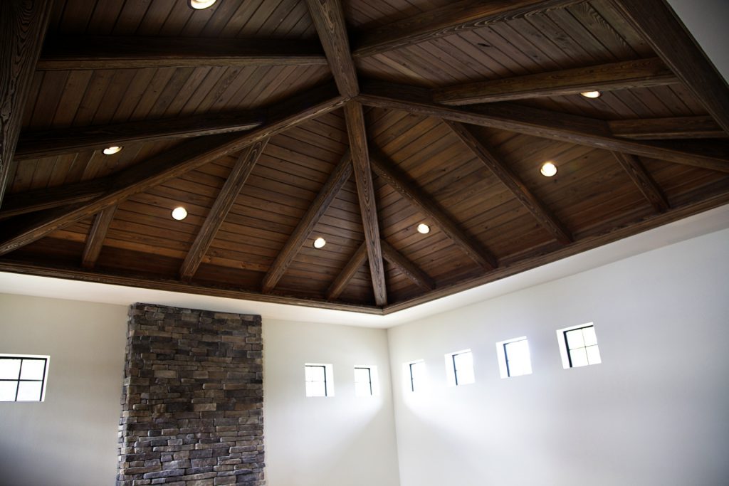Interior of a room with a high wooden ceiling and stone fireplace.