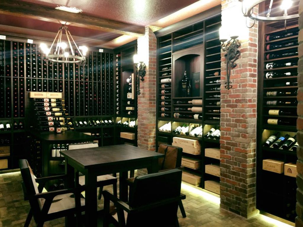 Cozy wine bar with wooden shelves and seating area under warm lighting.