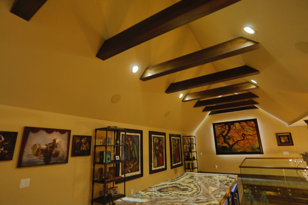 Interior of a warmly lit room with wooden beams and framed artwork.