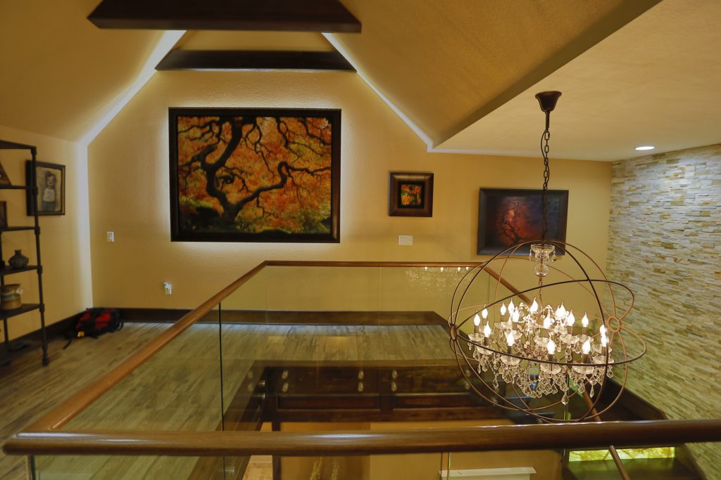 Warm attic room with framed art and a chandelier.