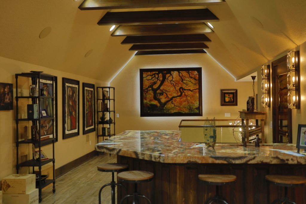 Cozy attic bar with warm lighting and framed art.