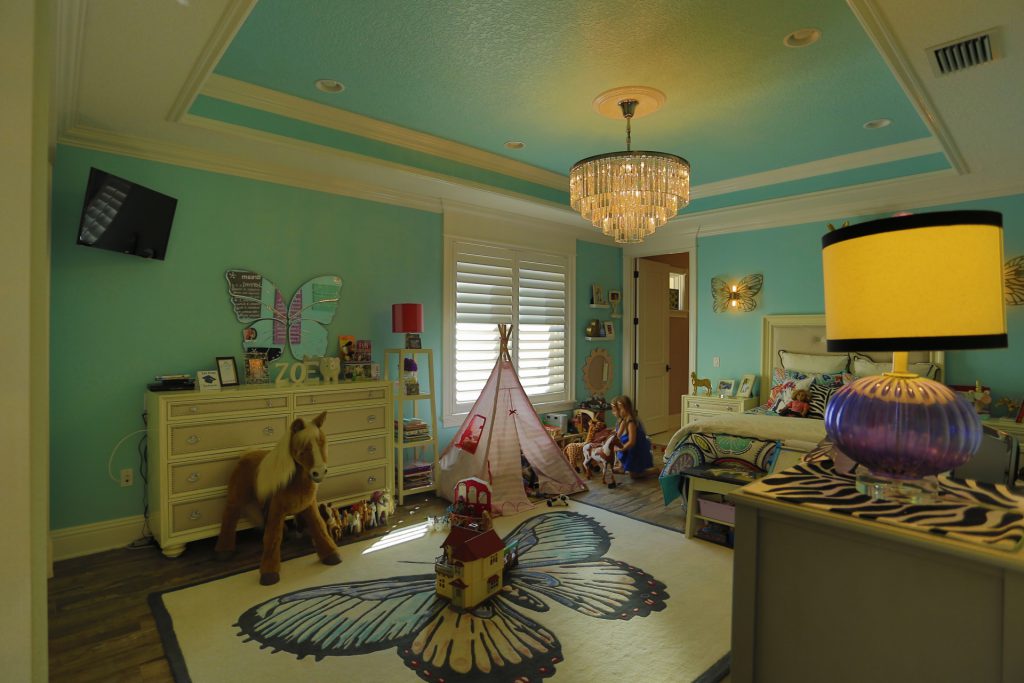 A cozy children's playroom with toys and a teepee under a chandelier.