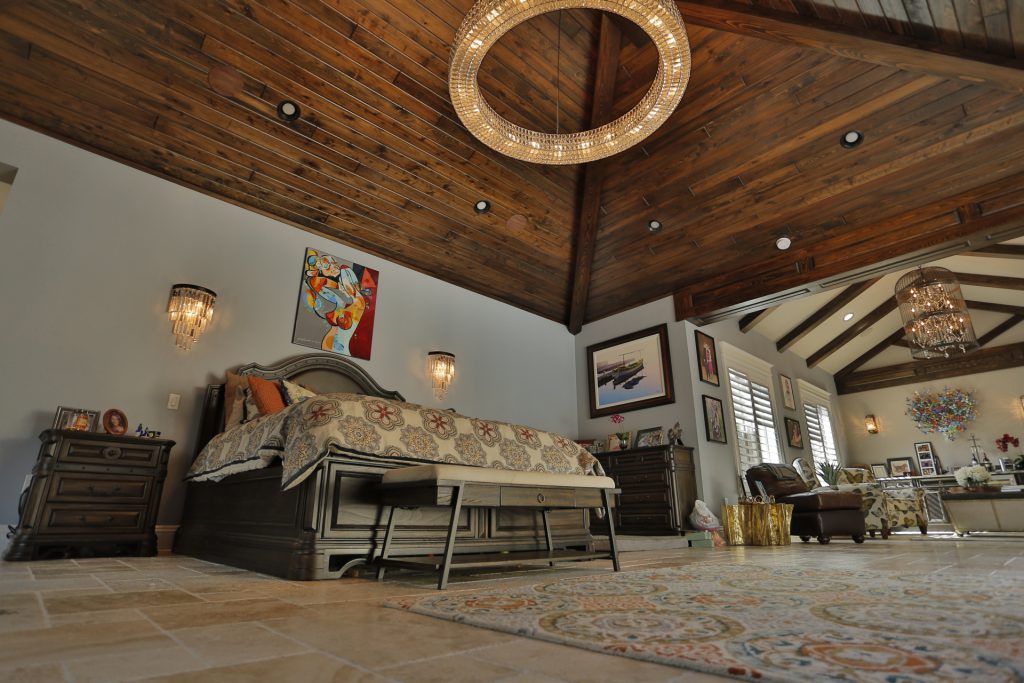 Cozy bedroom with wooden ceiling and modern lighting.