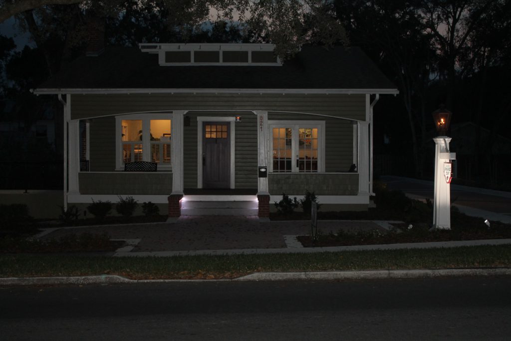 A cozy house warmly lit at night on a quiet street.