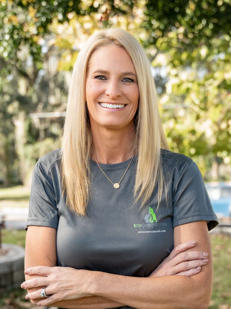 Smiling woman with long blonde hair wearing a gray t-shirt outdoors.